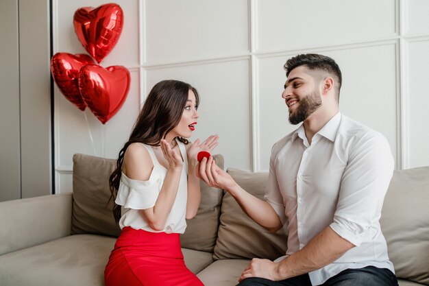 Mens die verloofde met een ring en hartvormige ballons thuis in flat voorstellen