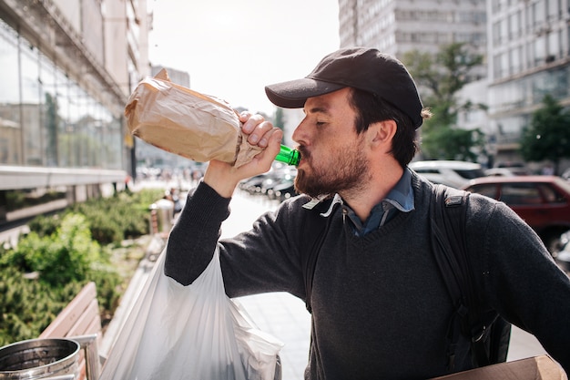 Mens die zich op de straat bevindt en van fles drinkt