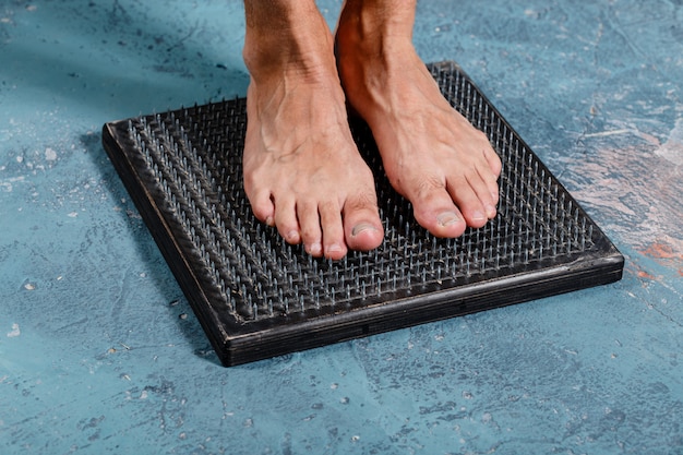 Mens die zich op natuurlijke voet houten massager bevinden met schoenspijkers