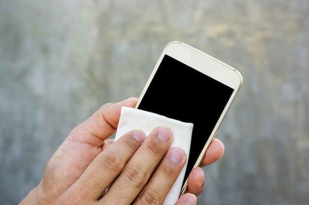 Mens die zijn smartphone met een microfiberdoek schoonmaakt