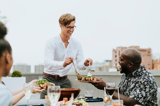 Foto mens die zijn vriendensalade dient bij een dakpartij