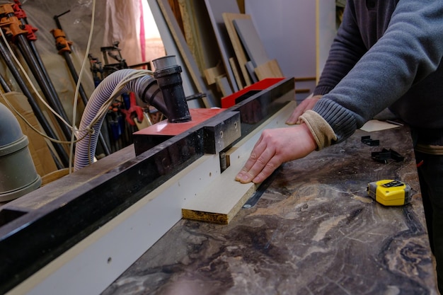 Photo mens hand sawing wood on circular saw machine which saws wood particle board and fiberboard production of furniture selective focus