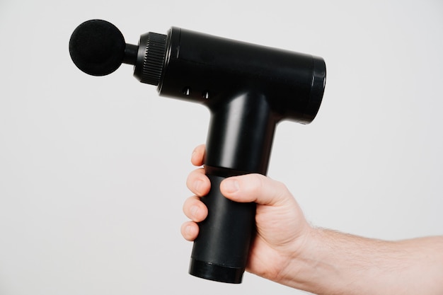 Mens hands holds massage gun. medicalsports device helps to reduce muscle pain after training