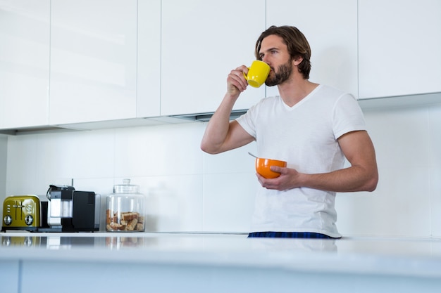 Mens het drinken koffie terwijl het hebben van ontbijt in keuken