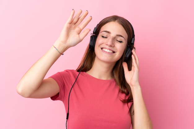 Mens het luisteren muziek over geïsoleerde roze muur