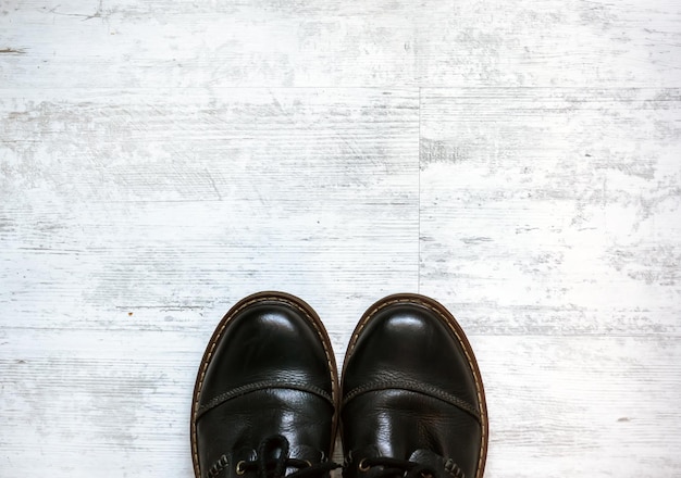 Mens in bruine schoenen die zich op de houten vloerachtergrond bevinden