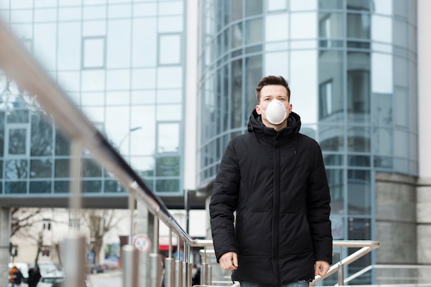 Mens in de stad die jas en medisch masker draagt