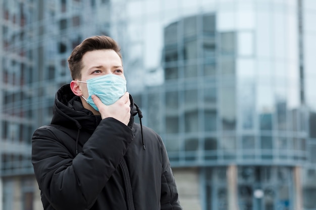 Foto mens in de stad die medisch masker en jasje draagt