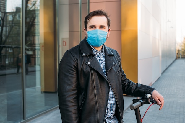 Mens in de straat die beschermend masker in elektrische autoped draagt. Zieke man met griep masker dragen, epidemische griep concept op straat.