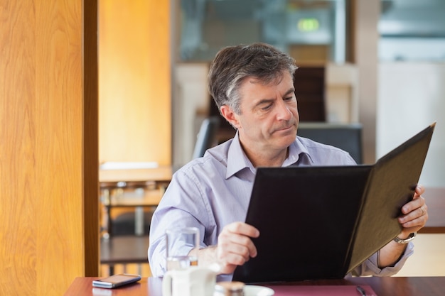 Mens in een koffiewinkel die het menu bekijkt