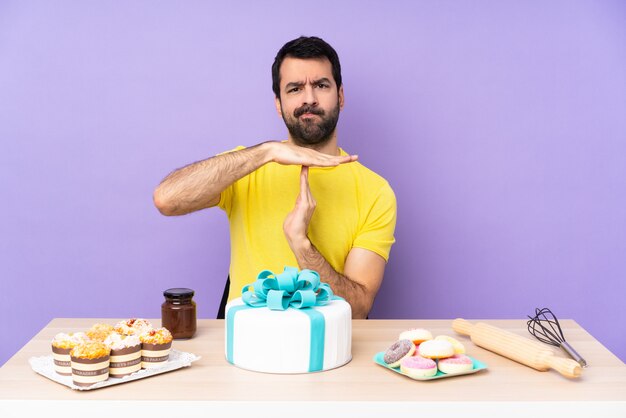 Mens in een lijst met een grote cake die time-out gebaar maakt