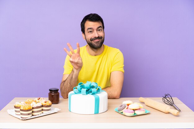 Mens in een lijst met een grote gelukkige cake en het tellen van drie met vingers