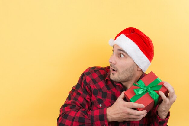 Mens in een rode hoed die een gift van Kerstmis houdt