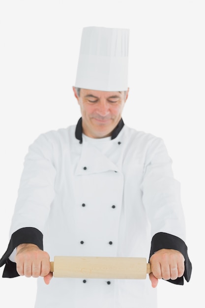 Mens in eenvormige chef-kok gebruikend deegrol