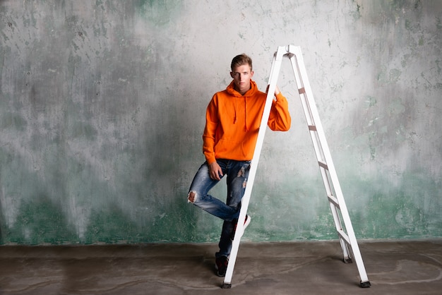 Foto mens in het oranje hoodie stellen op een ladder