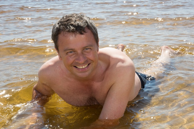 Mens in het water bij het strand gelukkig om in vakantie te zijn