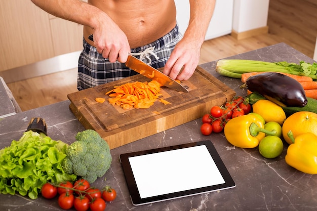 Mens in keuken die tablet gebruikt voor het koken van recept