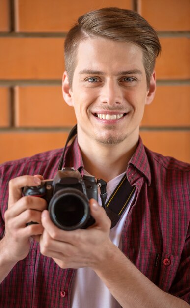 Mens in slimme vrijetijdskledingholding camera en het glimlachen.