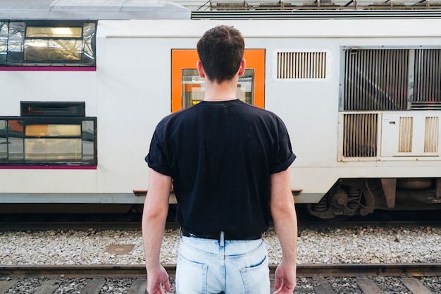 Foto mens in zwarte t-shirt die zich voor spoorwegtrein bevindt