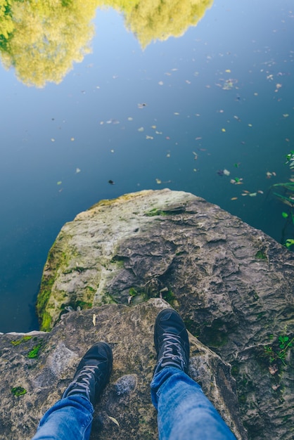 Mens legs stand on a stone in front of the lake Flooded stones in the water