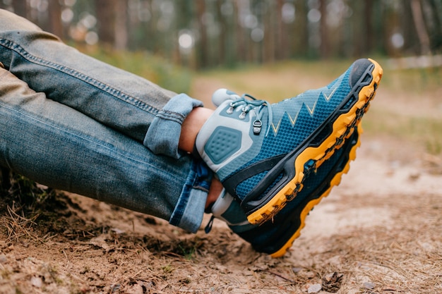 Photo mens legs in trekking boots for outdoor activity on forest road.