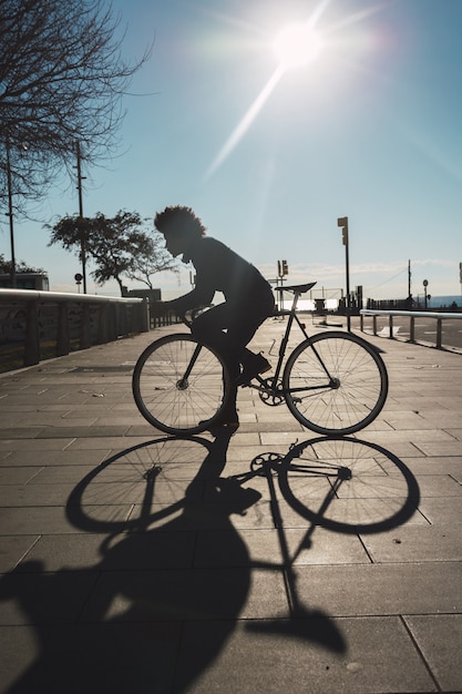 Mens met afrohaar die een uitstekende stijlfiets berijden