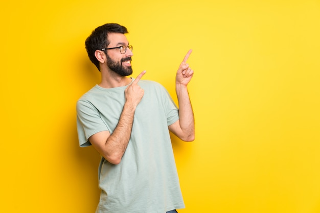 Mens met baard en groen overhemd die met de wijsvinger richten en omhoog eruit zien