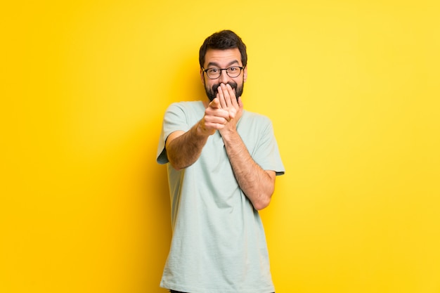 Mens met baard en groen overhemd die met vinger iemand richten en lachen