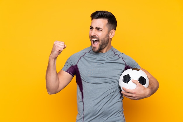 Mens met baard speelvoetbal over geïsoleerde muur