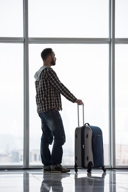 Mens met een koffer die op zijn vlucht wacht.