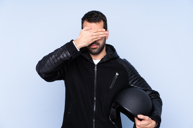 Mens met een motorhelm over geïsoleerde muur die ogen behandelt door handen. Wil niet iets zien