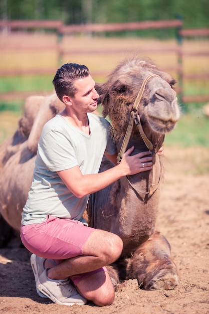 Mens met kameel in de dierentuin op warme en zonnige de zomerdag. actieve familie vrije tijd.