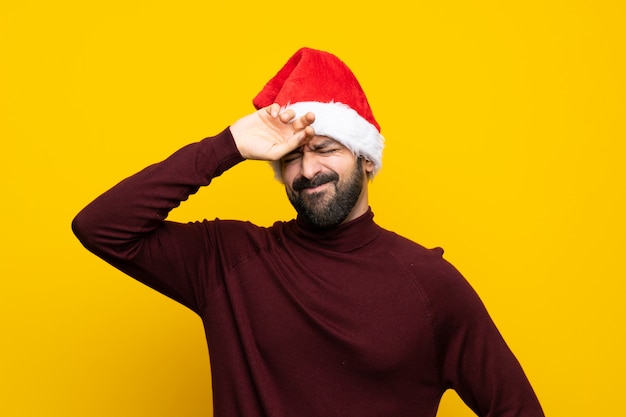 Mens met Kerstmishoed over geïsoleerde gele muur met vermoeide en zieke uitdrukking