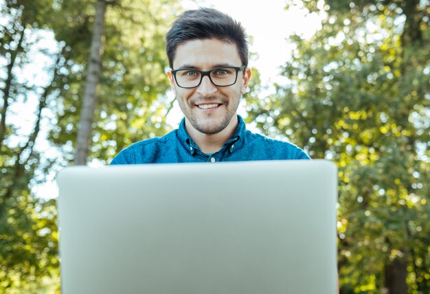 Mens met laptop zitting in openlucht in aard