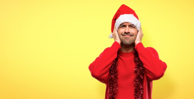 Mens met rode kleren die de Kerstmisvakantie vieren die beide oren behandelen