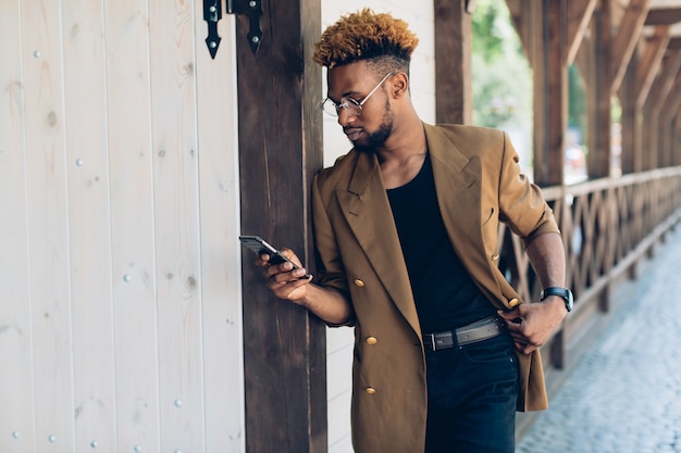 Mens met telefoon die op kolom leunt