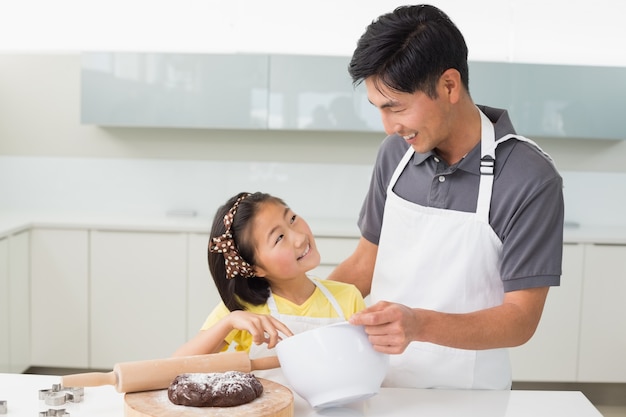 Mens met zijn dochter die deeg in keuken voorbereidt