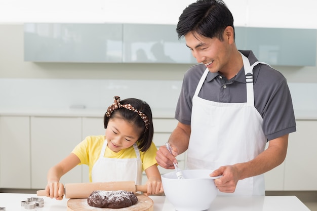 Mens met zijn dochter die koekjes in keuken voorbereidt