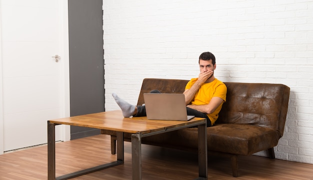 Mens met zijn laptop in een ruimte die mond behandelt met handen voor het zeggen van iets ongepast