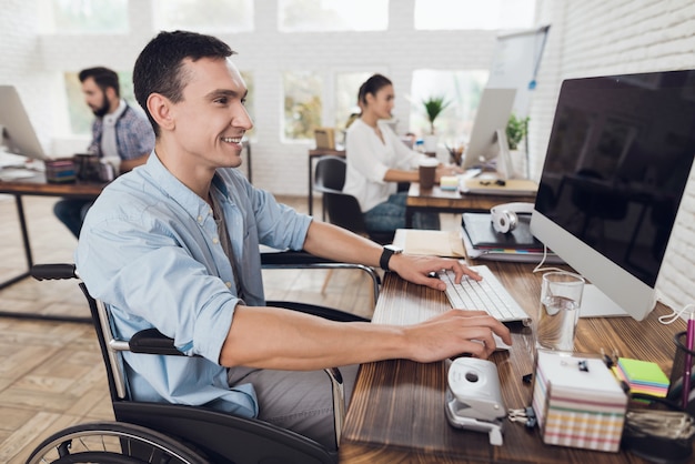 Mens op Rolstoel die aan Computer in Bureau werken.