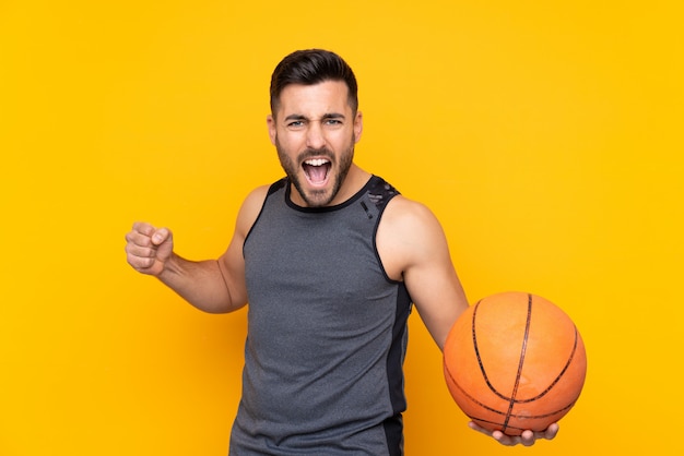 Mens over geïsoleerd geel muur speelbasketbal