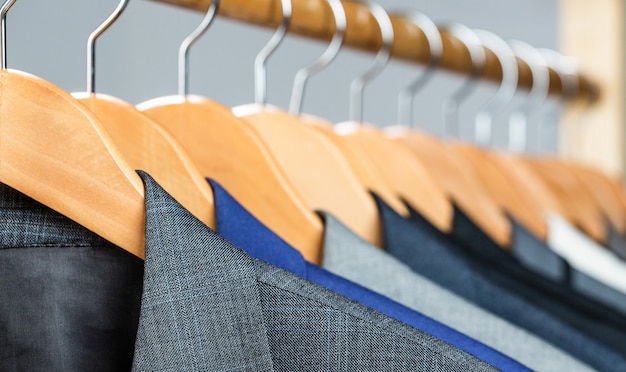 Mens shirts, suit hanging on rack. Hangers jackets on them in boutique