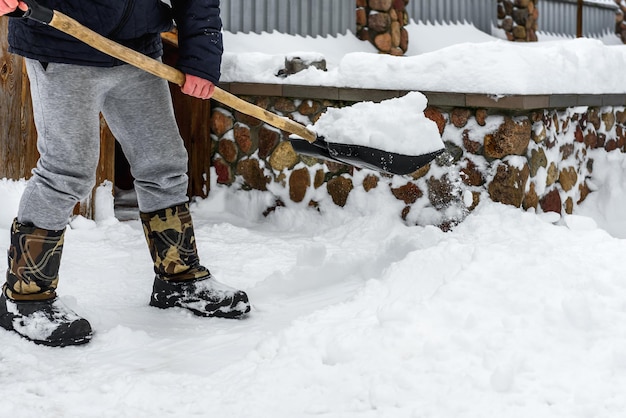 Foto mens sneeuw schoonmaken met een schop in de buurt van huis