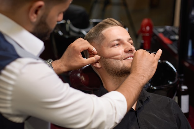 Mens tijdens procedure van het inpassen van baard in kapperswinkel