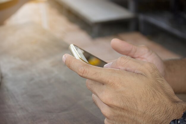 menselijk met behulp van touchscreen mobiele telefoon met Coffee Shop wazige achtergrond