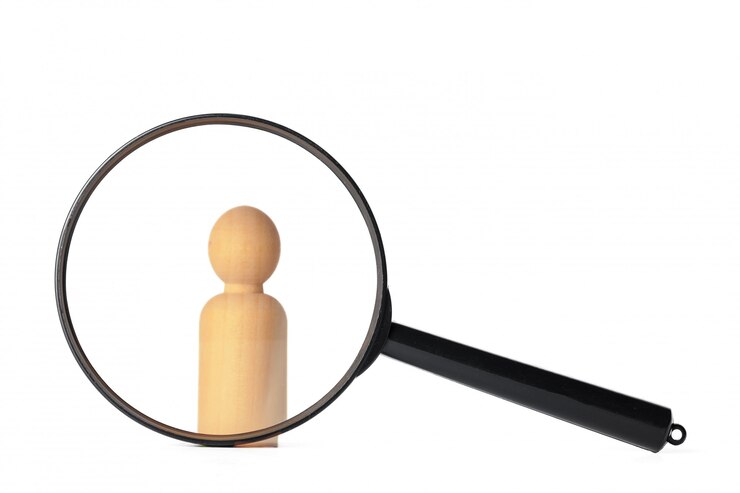 Foto menselijke figuur staat in de buurt van een vergrootglas. het concept van het zoeken naar mensen en werknemers. zoeken naar vacatures en werk. human resources management