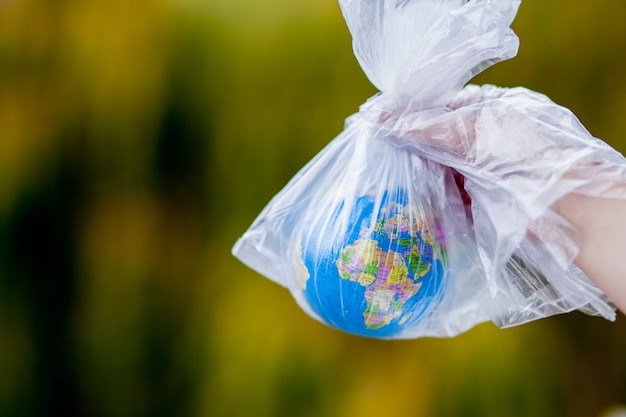 menselijke hand houdt de planeet aarde in een plastic zak