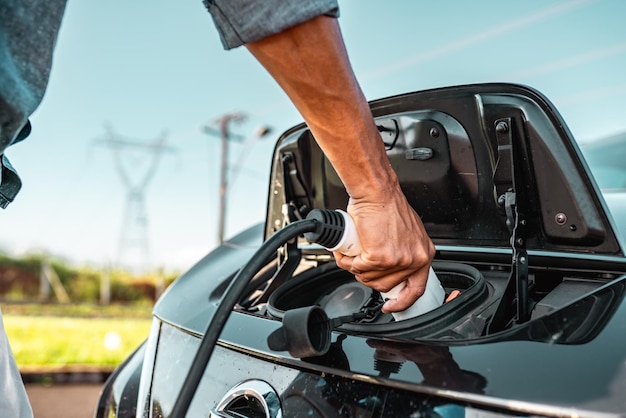 Menselijke hand houdt elektrische auto opladen verbinding met elektrische auto