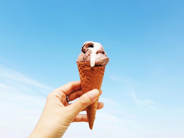 Foto menselijke hand met een ijsje tegen de lucht