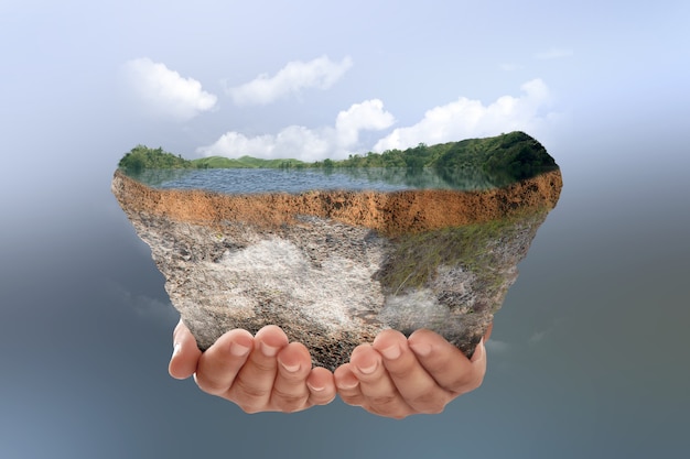 Foto menselijke hand met ondergrondse bodemlaag van doorsnede aarde met meer en heuvels op de top met gekleurde achtergrond